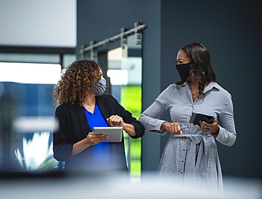 Businesswomen in face masks greeting with elbows in office