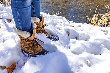 Legs of senior woman in hiking boots standing in snow