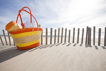 Beach bag with flip-flops on beach