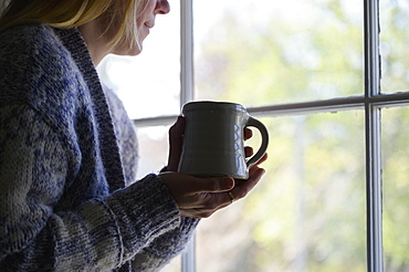 Woman holding mug and looking out window