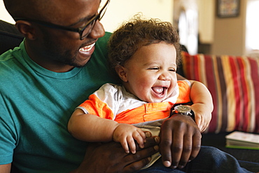 Father and baby laughing on sofa