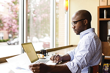 Black man using laptop in coffee shop