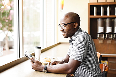 Black man using digital tablet in coffee shop