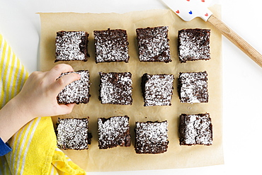 Overhead view of boys (6-7) hand reaching for freshly baked brownie