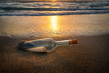 United States, Florida, Boca Raton, Glass bottle with message inside on beach at sunset