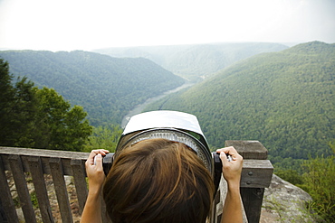 Mid adult woman looking through coin operated binoculars, rear view, New River Gorge National River, Fayetteville, West Virginia, USA