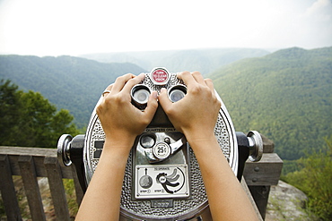 Mid adult woman holding coin operated binoculars, focus on hands, New River Gorge National River, Fayetteville, West Virginia, USA