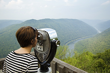 Mid adult woman looking through coin operated binoculars, rear view, New River Gorge National River, Fayetteville, West Virginia, USA