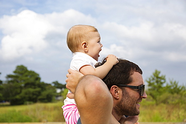 Mid adult man carrying baby daughter on shoulders