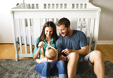 Mid adult couple playing with baby daughters fingers on lap