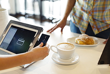 Customer paying for coffee in coffee shop, mid section