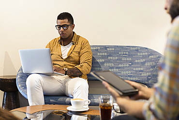 Young man in coffee shop, using laptop