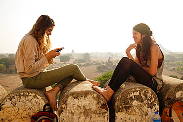 Women relaxing on stone wall, Bagan Archaeological Zone, Buddhist temples, Mandalay, Myanmar