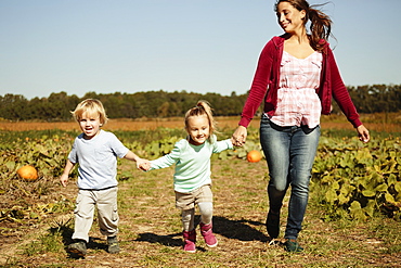 Mother with two children running in pumpkin field