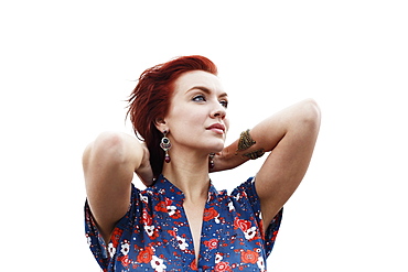 Portrait of young woman, hands behind neck, looking away