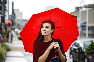 Young woman with red hair, holding red umbrella