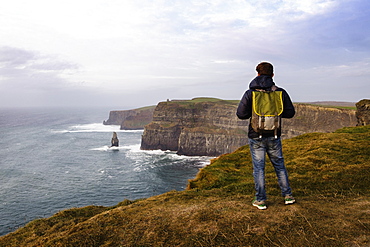 Mid adult man standing on The Cliffs of Moher, The Burren, County Clare, Ireland