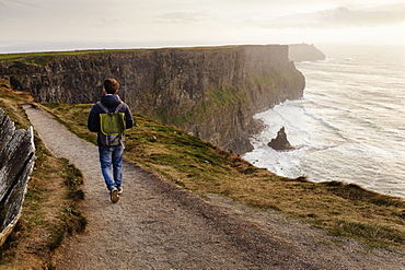 Mid adult man walking on The Cliffs of Moher, The Burren, County Clare, Ireland