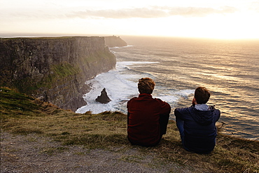 Two men sitting on The Cliffs of Moher, The Burren, County Clare, Ireland