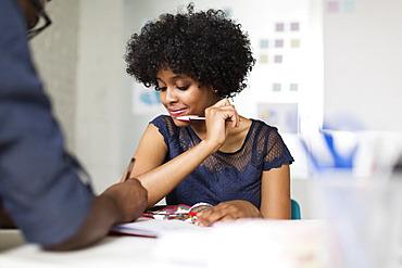 Two colleagues working, woman holding pen