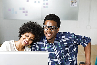 Young couple using computer, woman's head on man's shoulder