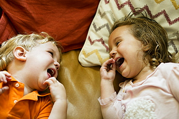 Male and female toddler friends giggling on sofa