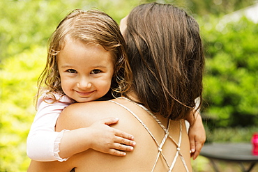 Portrait of female toddler carried by mother in garden