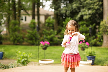 Female toddler preparing to blow bubbles in garden