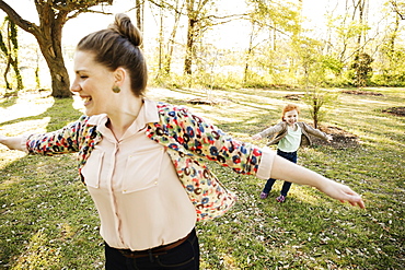 Mid adult mother and daughter playing on grass in park