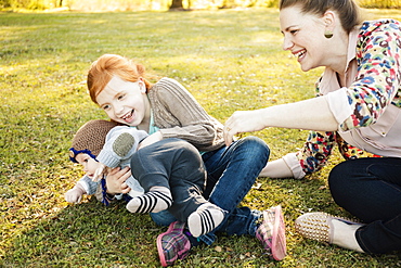 Mid adult mother, daughter and baby son on grass in park