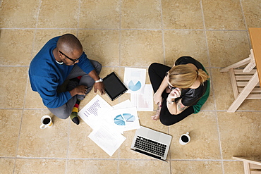 Young business partners sitting on floor in design office