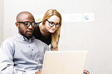 Young business partners looking at computer in design office