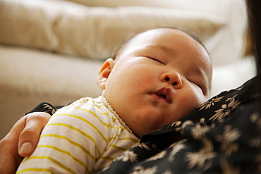 Close up of baby girl sleeping in mothers arms