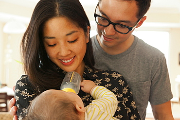 Mother feeding baby daughter whilst father watches