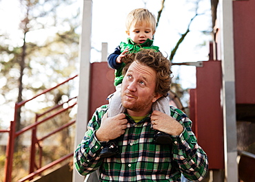 Father carrying son on shoulders in park