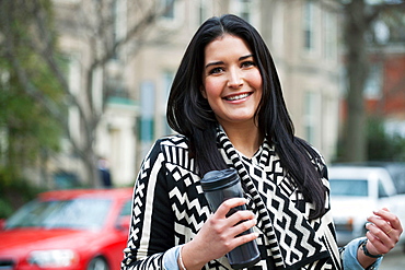 Young woman carrying travel mug