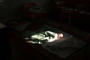 Baby boy sleeping in sunspot in bedroom