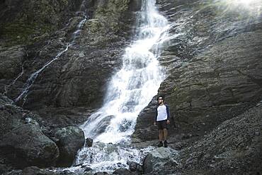 Russia, Karachay-Cherkessia, Arkhyz, Man standing near Sofiyskiye Vodopady waterfall in Caucasus Mountains