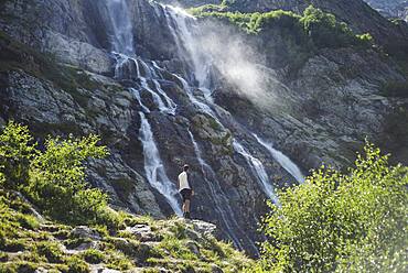 Russia, Karachay-Cherkessia, Arkhyz, Man standing near Sofiyskiye Vodopady waterfall in Caucasus Mountains