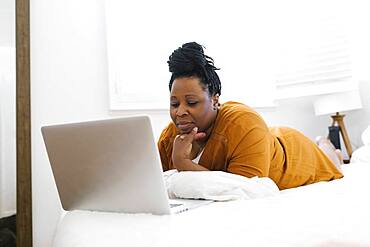 Woman working on laptop in bed