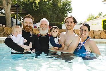 Portrait of family with boys (12-17 months, 2-3) in swimming pool