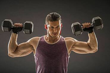 Muscular man training with dumbbells