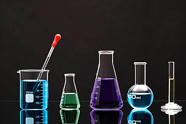 Laboratory glassware with liquids against black background