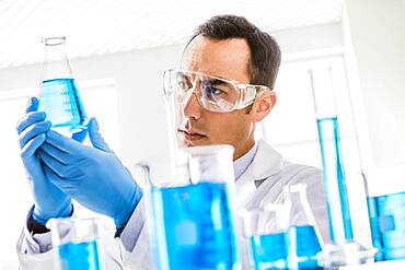 Scientist looking at blue liquid in laboratory