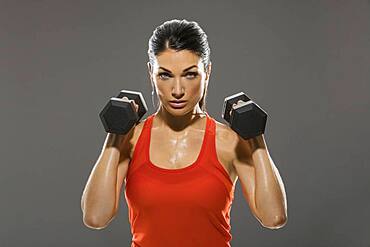 Studio portrait of woman exercising with dumbbells