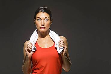 Studio portrait of athletic woman in red sleeveless top holding towel