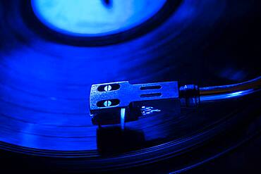 Close-up of a record player needle on record in blue light