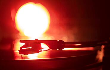 Close-up of a record player needle on record in orange light