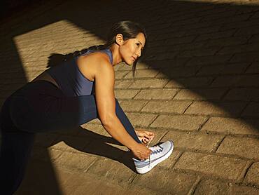 Athletic woman tying sport shoe outdoors