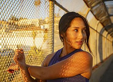 Athlete woman stretching at fence